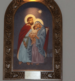 Religious painting of the Holy Family framed in an ornate wooden border.