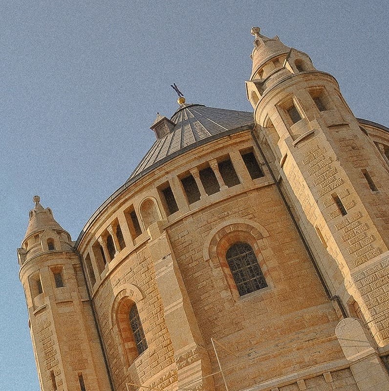 istoric stone church with towers and a domed roof against a clear blue sky.