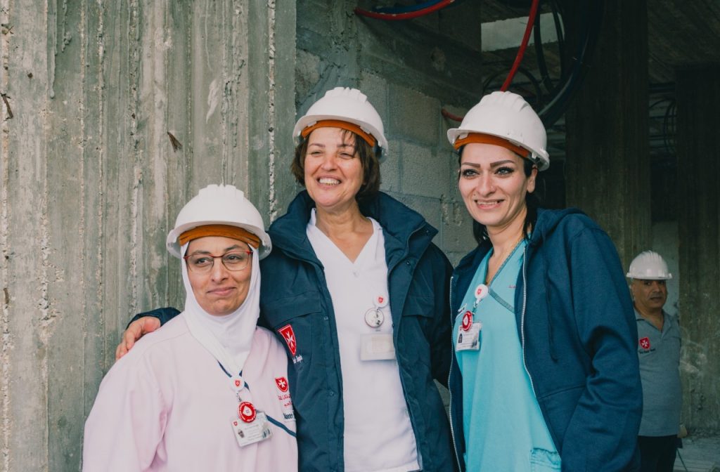 three women wearing white construction hats smiling.
