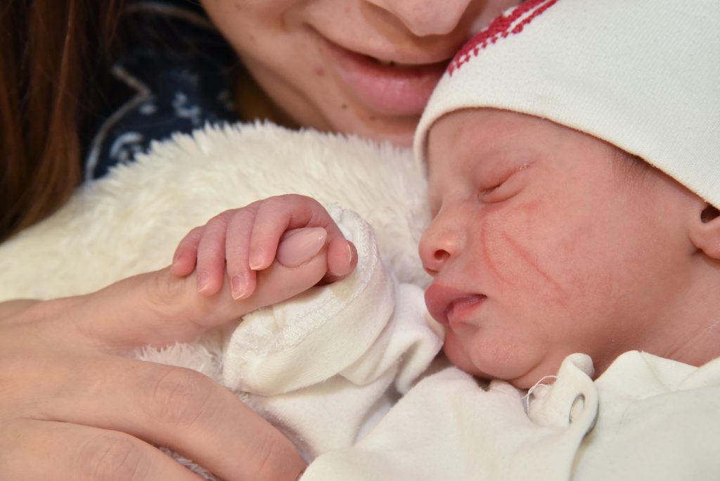 baby holding moms finger